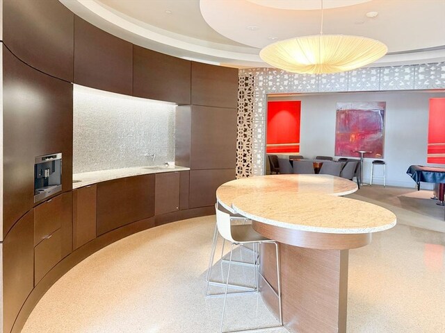 kitchen featuring light countertops, decorative light fixtures, light carpet, and backsplash
