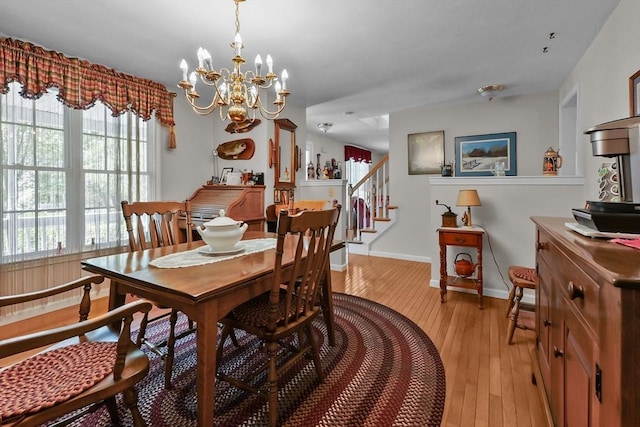 dining room featuring baseboards, a notable chandelier, stairway, and light wood-type flooring