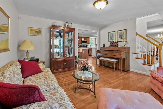 living room with a chandelier, light wood-style flooring, and stairs