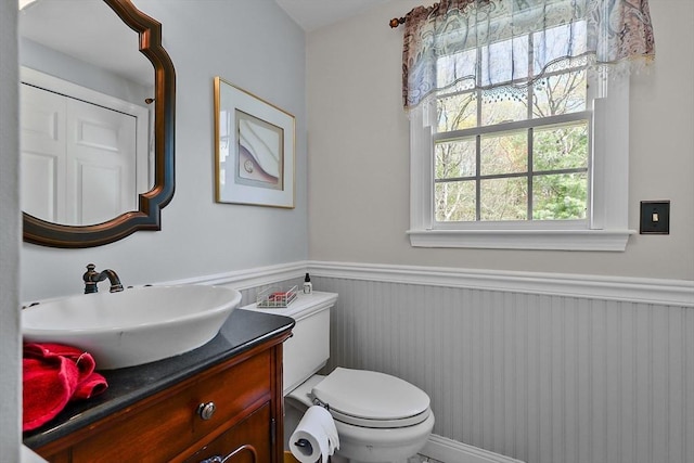 bathroom featuring toilet, wainscoting, and vanity