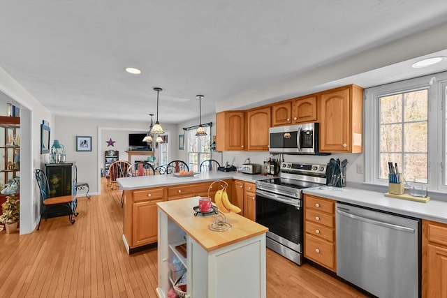 kitchen featuring pendant lighting, recessed lighting, a peninsula, light wood-style floors, and stainless steel appliances
