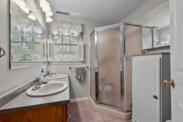 full bathroom with a shower stall, tile patterned floors, double vanity, and a sink