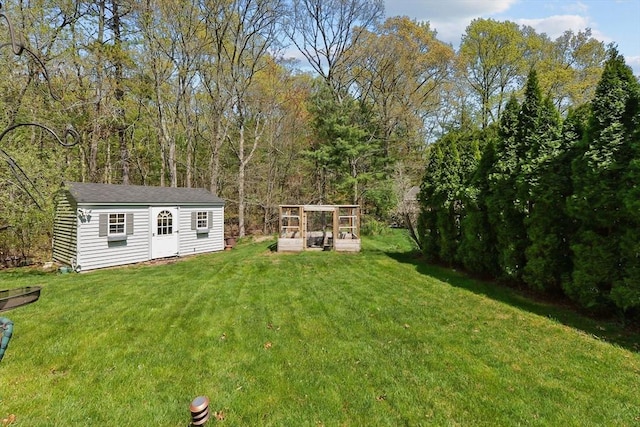 view of yard featuring a wooded view and an outbuilding