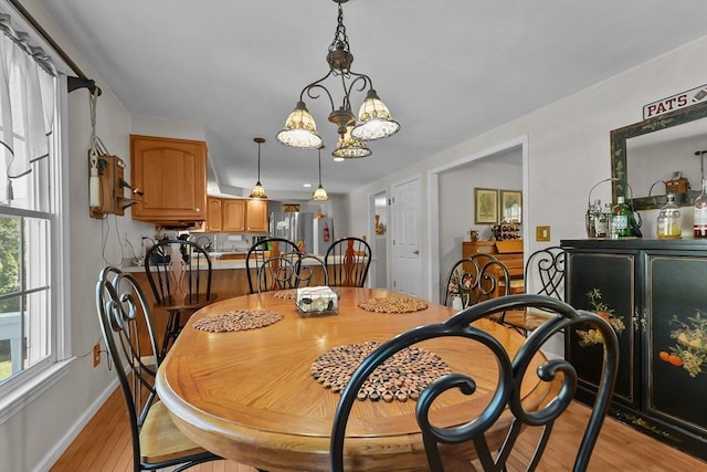 dining room featuring light wood finished floors, baseboards, and a chandelier