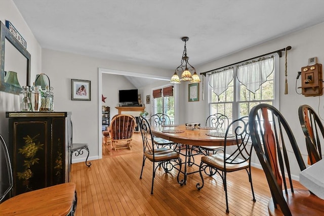 dining room with a chandelier, light wood-style flooring, and baseboards