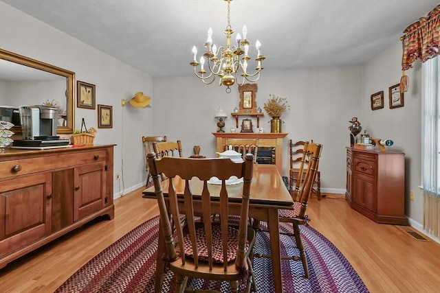 dining room featuring baseboards, a notable chandelier, light wood-style flooring, and visible vents