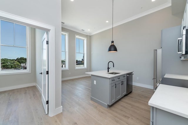 kitchen with stainless steel appliances, ornamental molding, a sink, and a wealth of natural light