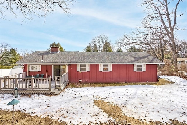 view of front of property with a shingled roof, a chimney, and a deck