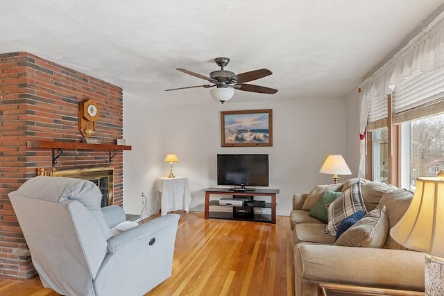 living area with a ceiling fan, a fireplace, and wood finished floors