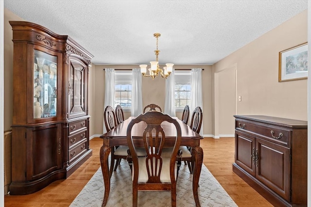 dining room featuring a chandelier, light hardwood / wood-style floors, and a textured ceiling