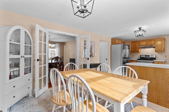 dining area featuring french doors, a textured ceiling, and a notable chandelier