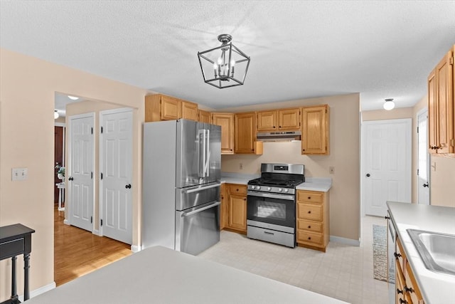 kitchen featuring pendant lighting, stainless steel appliances, light brown cabinetry, and a chandelier