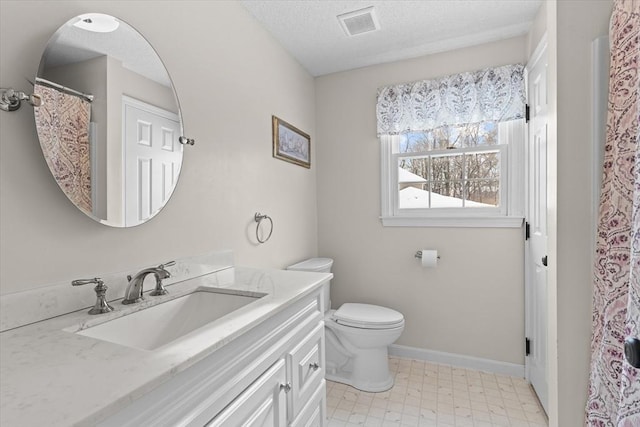 bathroom with vanity, toilet, and a textured ceiling