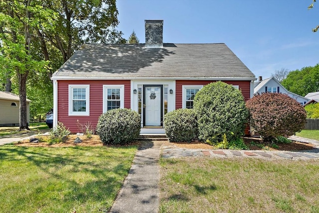 cape cod house featuring a chimney and a front yard