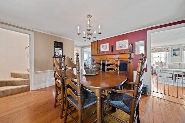 dining room featuring crown molding, stairway, wainscoting, a chandelier, and hardwood / wood-style flooring
