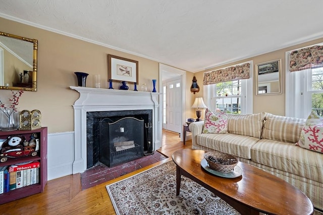 living area featuring ornamental molding, a fireplace with flush hearth, plenty of natural light, and wood finished floors