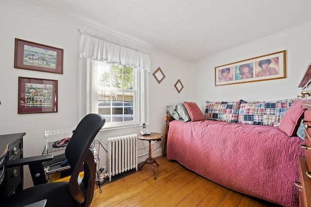 bedroom with radiator and light wood-style flooring