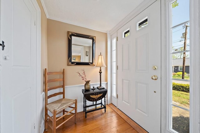 foyer with crown molding and light wood-style floors