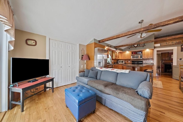 living area with light wood finished floors, ceiling fan, and vaulted ceiling with beams