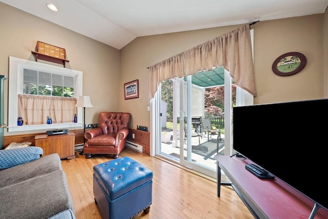 living area with lofted ceiling, a baseboard heating unit, baseboard heating, and light wood-type flooring