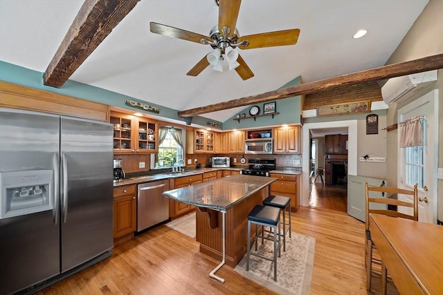 kitchen featuring a sink, stainless steel appliances, an AC wall unit, and light wood-style floors