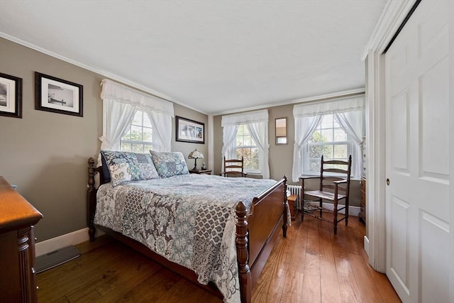 bedroom with baseboards, radiator, hardwood / wood-style floors, and crown molding