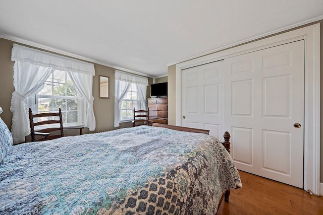 bedroom featuring ornamental molding, a closet, and wood finished floors