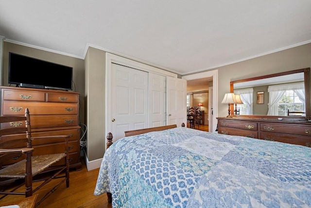 bedroom with crown molding, a closet, wood finished floors, and baseboards