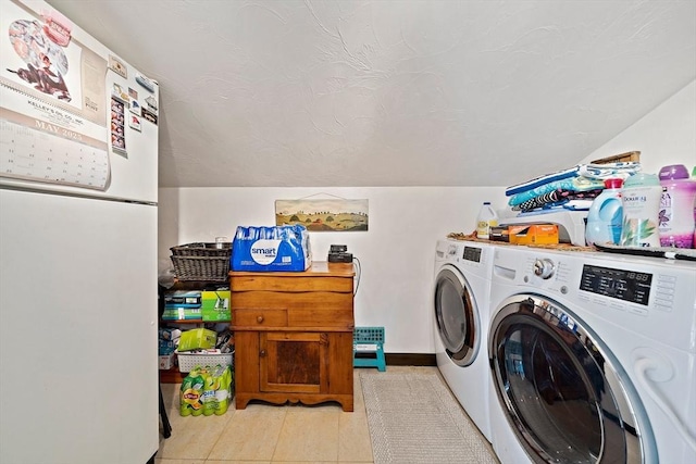 clothes washing area featuring light tile patterned floors, separate washer and dryer, and laundry area