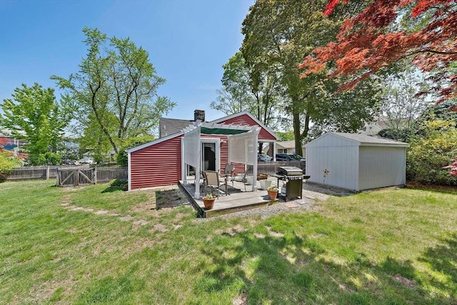 rear view of property featuring a chimney, an outdoor structure, a fenced backyard, a yard, and a patio area