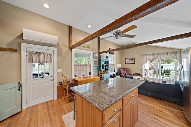 kitchen featuring a center island, light wood-style flooring, freestanding refrigerator, lofted ceiling with beams, and ceiling fan