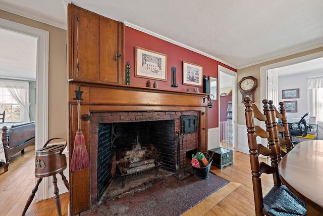living area featuring light wood-style flooring, a fireplace, and ornamental molding