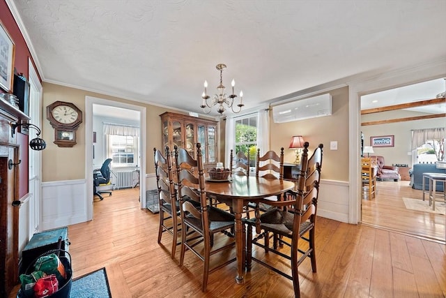 dining area featuring radiator, a wall mounted air conditioner, light wood-style floors, and an inviting chandelier
