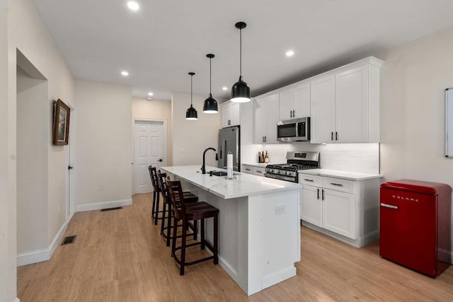 9-11 Dexter, Boston, MA 02127 - kitchen with appliances with stainless steel finishes, a kitchen island with sink, a sink, a breakfast bar, and light wood-style floors