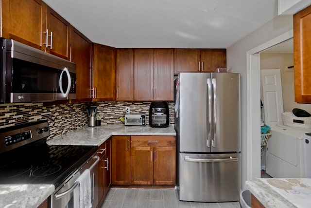 kitchen with light stone countertops, stainless steel appliances, separate washer and dryer, and tasteful backsplash