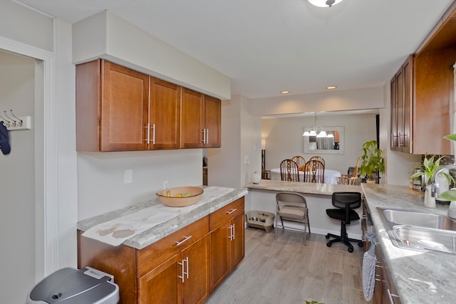 kitchen featuring built in desk, hanging light fixtures, light hardwood / wood-style floors, sink, and a notable chandelier