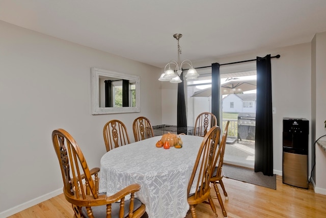 dining room with light wood-type flooring and an inviting chandelier