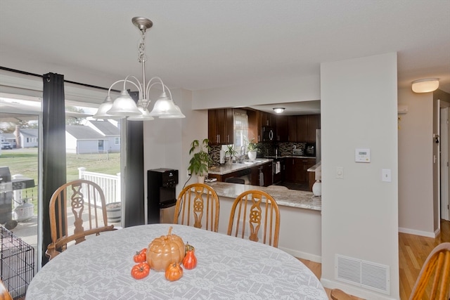 dining area featuring light wood-type flooring and an inviting chandelier