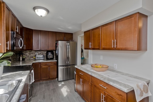 kitchen featuring light wood-type flooring, decorative backsplash, light stone countertops, and stainless steel appliances