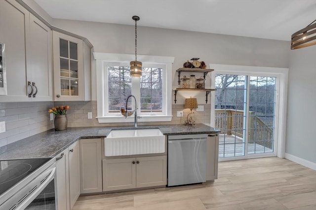 260 Main St Unit 12, Blackstone, MA 01504 - kitchen featuring appliances with stainless steel finishes, a sink, decorative backsplash, dark stone counters, and glass insert cabinets