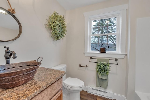 260 Main St Unit 12, Blackstone, MA 01504 - half bathroom featuring a baseboard heating unit, toilet, vanity, wood finished floors, and baseboards