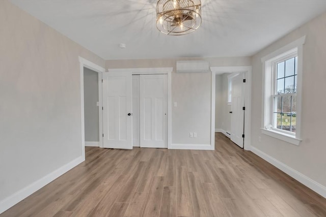 260 Main St Unit 12, Blackstone, MA 01504 - unfurnished bedroom with an AC wall unit, light wood-style floors, a chandelier, and baseboards