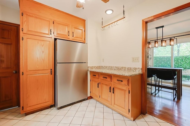 kitchen featuring freestanding refrigerator, recessed lighting, light stone counters, and light brown cabinets