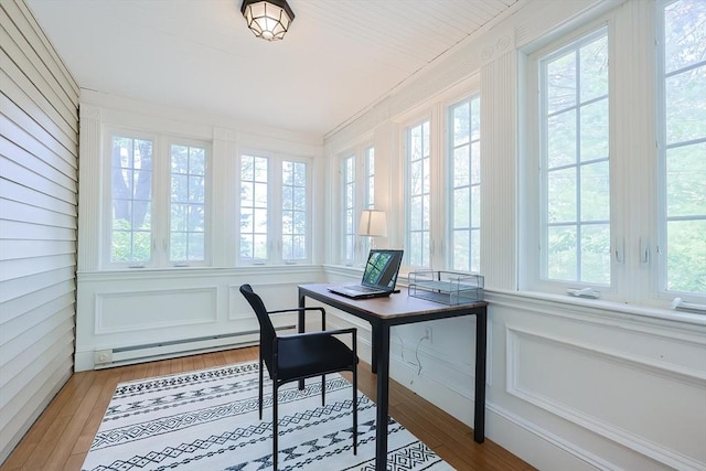 office space featuring a baseboard heating unit and light wood finished floors