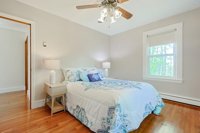 bedroom featuring a ceiling fan, baseboards, a baseboard heating unit, and hardwood / wood-style flooring