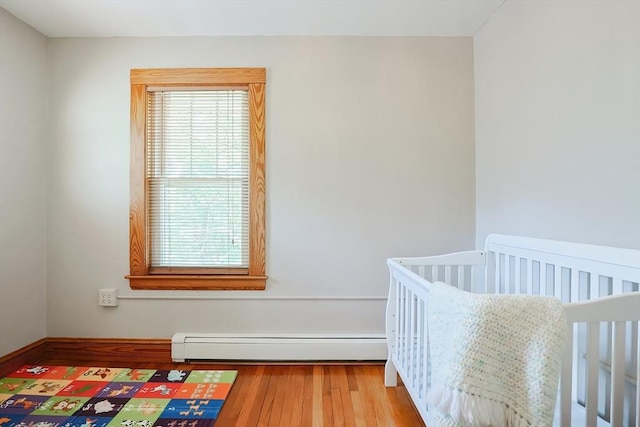 bedroom featuring multiple windows, baseboard heating, and wood finished floors