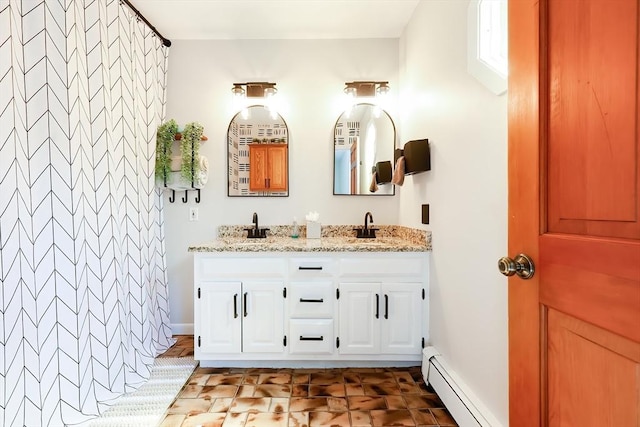 bathroom featuring double vanity, baseboards, baseboard heating, and a sink