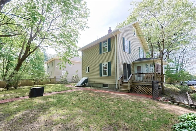 back of property featuring a lawn, a fenced backyard, a wooden deck, and a chimney