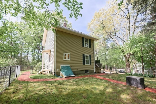 rear view of property with a lawn, a gate, a fenced backyard, and a chimney