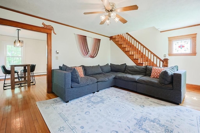living area featuring ornamental molding, wood-type flooring, a ceiling fan, and stairs